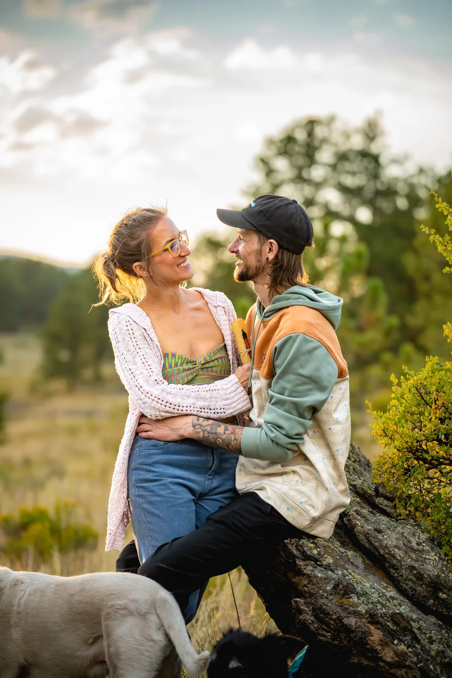 DJ and Kim smiling at each other at sunset, with their dogs at their feet